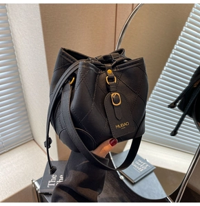 Détail du sac seau en cuir noir matelassé avec cordon et finitions dorées mates