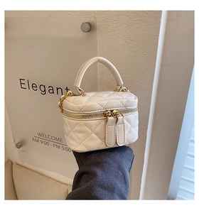 Detail of cream white quilted mini bucket bag with gold zippers and chain strap