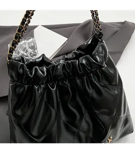 Close-up of black quilted bucket bag with chain strap and gold letter K metal logo