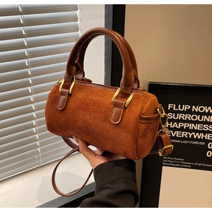 Detailed view of the orange suede Boston bag with brown leather handles and gold metal hardware