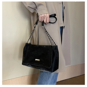 Détail du sac cabas en velours noir avec plaque dorée et bandoulière en chaîne
