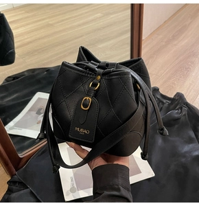 Détail du sac seau noir matelassé avec fermeture à cordon et boucles métalliques dorées