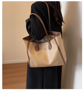 Detailed view of the khaki leather tote bag featuring brown straps and branding logo