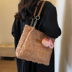 Borsa tote marrone intrecciata con catena e ciondolo di peluche portata a spalla