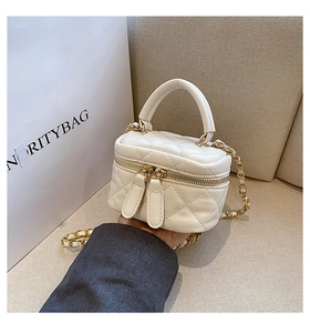 Macro detail of white quilted leather mini vanity bag with gold chain strap
