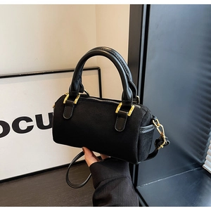 Detail of black suede Boston bag showing sleek cylinder shape and gold hardware accents