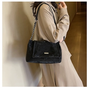 Détail du sac cabas noir givré avec bandoulière chaîne et plaque logo métallique