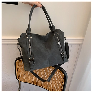Détail du cabas gris foncé mat avec fermetures éclair décoratives sur une chaise
