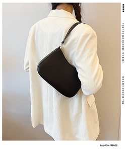 Detailed view of black leather underarm bag with silver hardware and sleek strap