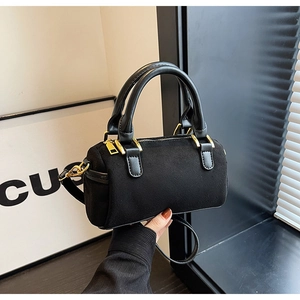 Detailed shot of black matte cylinder bag featuring gold hardware and double handles