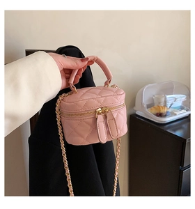 Close-up of pink quilted leather mini bucket bag with gold chain strap and dual zippers