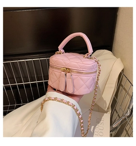Detailed macro view of pink quilted PU leather bag with golden zippers and chain strap