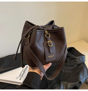 Vue détaillée du sac seau matelassé marron foncé avec détails dorés et bandoulière