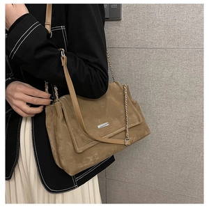 Détail du cabas mat chameau avec chaîne argentée sur une veste de blazer noire
