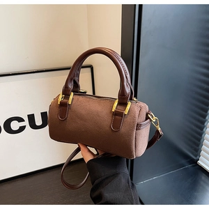Detailed close-up of brown suede Boston bag showing gold hardware and smooth leather strap