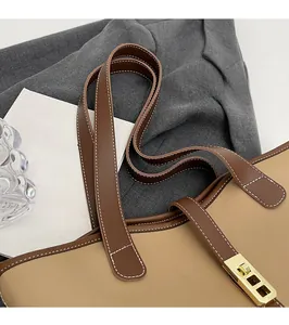 Macro detail of khaki tote bag featuring dark brown leather strap and gold metal lock
