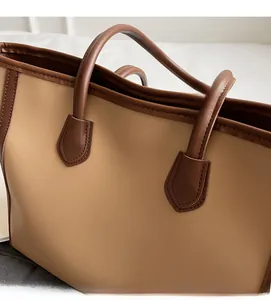 Detail of contrast color stitching and golden logo on Maillard style leather tote bag