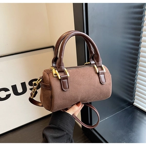 Detail of matte brown Boston cylinder bag showing golden hardware and suede texture
