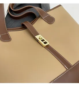 Detailed close-up of large tote bag featuring two-tone leather and golden metal hardware