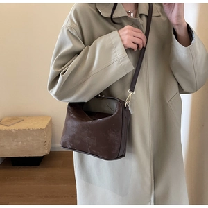 Gros plan d'un sac bandoulière marron vintage en cuir mat porté par un mannequin