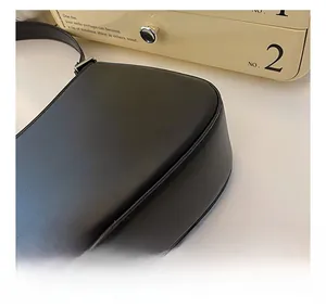 Close-up of the precise stitching craftsmanship on a black matte leather underarm bag