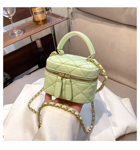 Detail of mint green quilted leather bag with gold-tone chain and metallic hardware