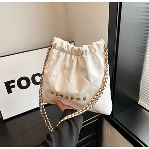 Detail of white quilted bucket bag featuring gold chain and CLEAR K metal logo