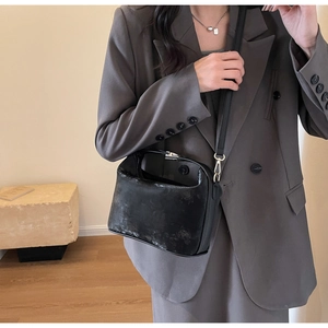 Gros plan détaillé du sac en cuir synthétique noir texturé avec boucle en métal argenté
