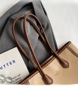 Detail of a bicolored tote bag showing stitched handles and logo on a blazer background