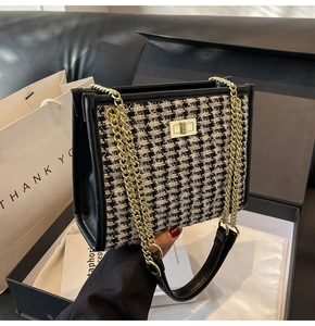 Close-up of houndstooth crossbody bag with golden chain and metallic twist lock