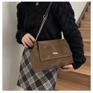 Détail du sac cabas en cuir mat marron avec bandoulière en chaîne et plaque logo argentée