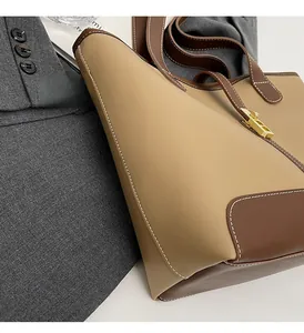 Detail of two-tone tote bag featuring contrast stitching and a gold twist-lock closure