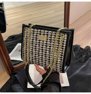 Detail of houndstooth tweed pattern with golden twist lock and metal chain strap