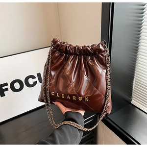 Detail of dark brown quilted leather chain bag with gold metal logo and drawstring closure