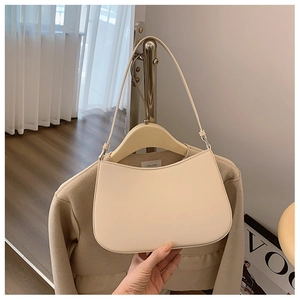 Detail of a creamy white crescent underarm bag in smooth leather with zipper and strap