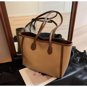 Detail of minimalist beige and brown leather tote bag with brand logo and stitching