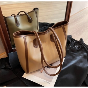 Close-up of beige and brown tote bag featuring fine leather texture and slim dual handles