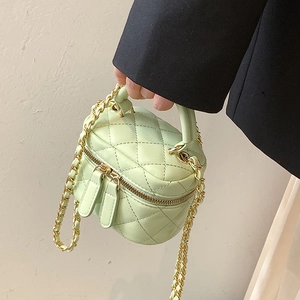 Mint green quilted mini bucket bag with gold chain strap held by a model