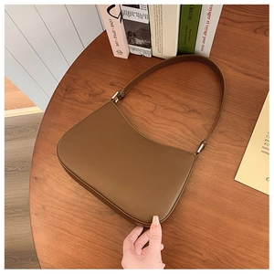 Top view of a brown leather hobo bag with silver hardware on a wooden table setup