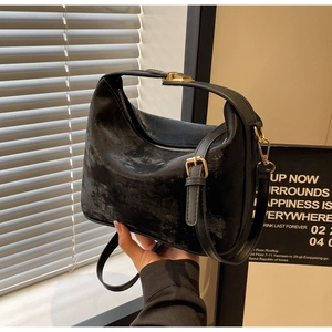 Détail d'un sac à bandoulière vintage en cuir noir mat avec finitions dorées