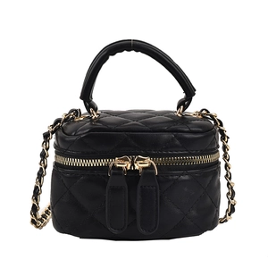 Elegant black quilted mini vanity bag with gold chain strap and top handle in studio view