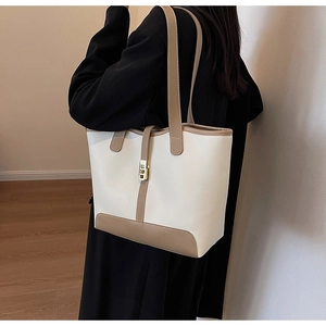 Side view of a large white tote bag with khaki trim and golden Jackie-style metal clasp