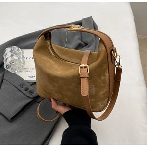 Détail du sac hobo en daim marron avec fermeture éclair dorée et boucles métalliques