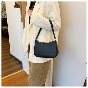 Detail of a minimalist black crescent underarm bag with silver hardware on shoulder