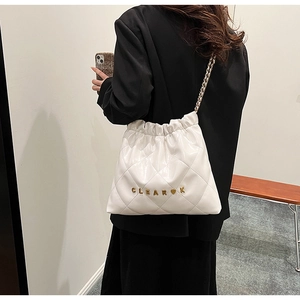 Close-up of white quilted shiny leather bucket bag with gold chain strap and metal logo
