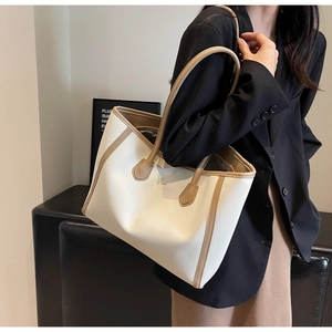 Detail of minimalist cream tote bag with contrast tan straps and gold foil logo accent
