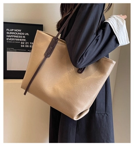 Detail of large khaki tote bag with pleated leather texture and dark brown shoulder straps