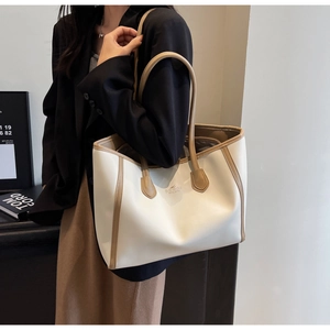 Detail of minimalist tote bag showing contrast trim, long handles and brand logo detail
