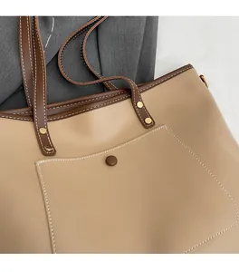 Detail of contrast stitch beige tote bag featuring brown front pocket and metal snap button