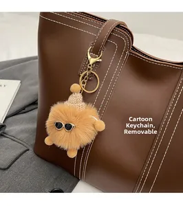 Plush cartoon charm with sunglasses on a brown leather tote bag, detachable detail